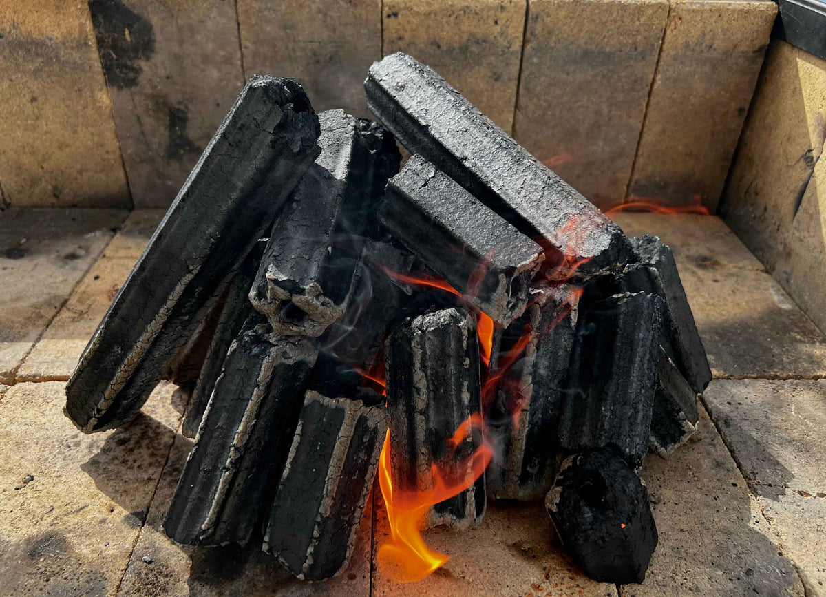 Globaltic hexagonal charcoal briquettes burning in a grill