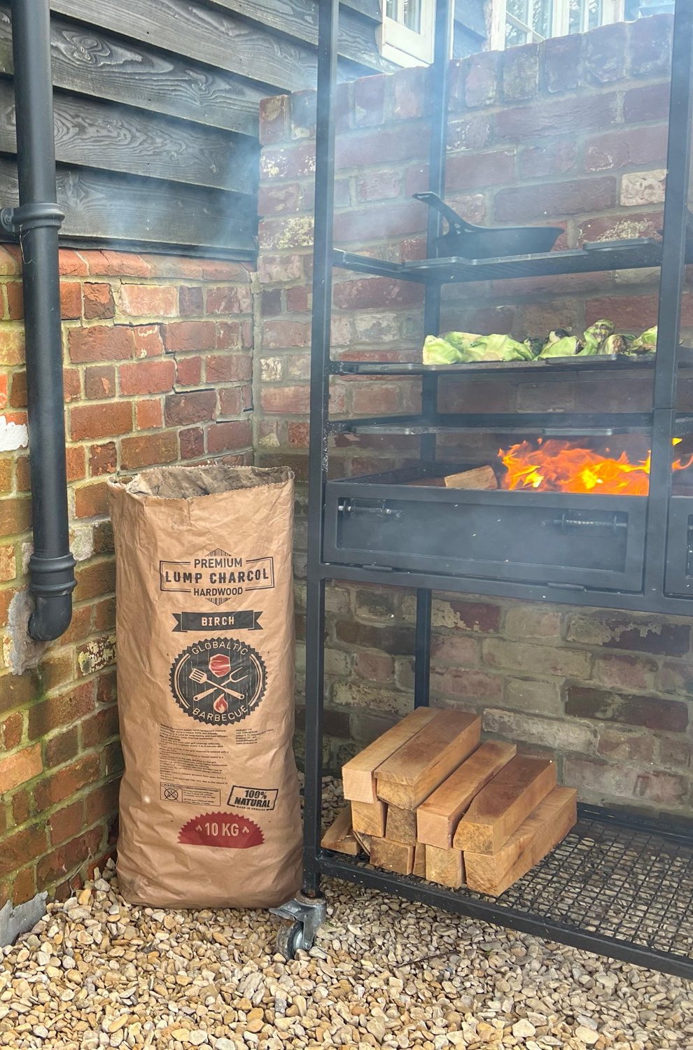 Globaltic 10kg birch lump charcoal bag beside an outdoor grill
